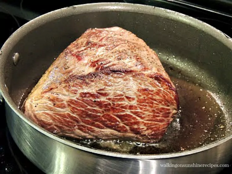 Brown the pot roast on all sides in a heavy pan on top of the stove.