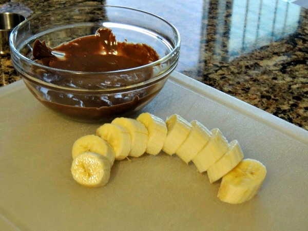 Sliced bananas and melted chocolate in bowl. 