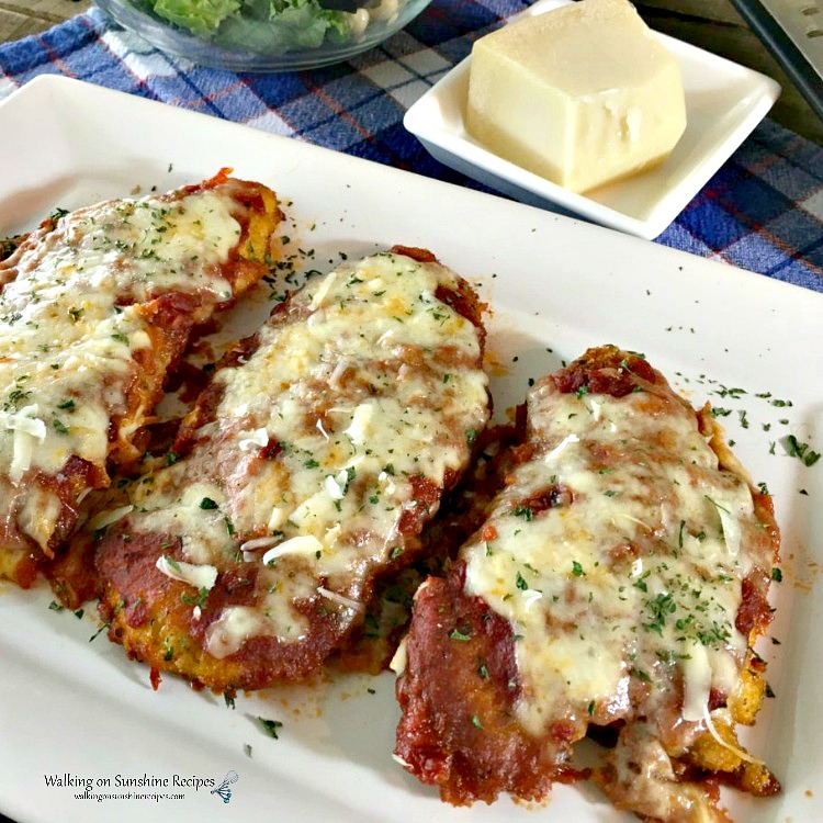Chicken Parmesan Baked on white platter with cheese and salad on side