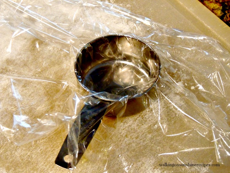Place plastic wrap over measuring cup