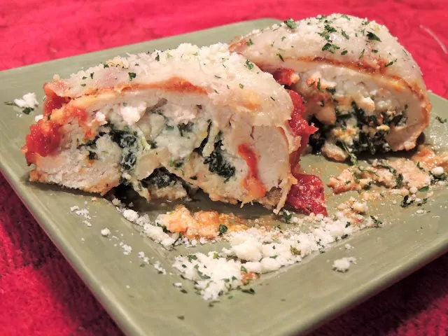Chicken Stuffed with Ricotta Cheese and Spinach on green plate closeup.