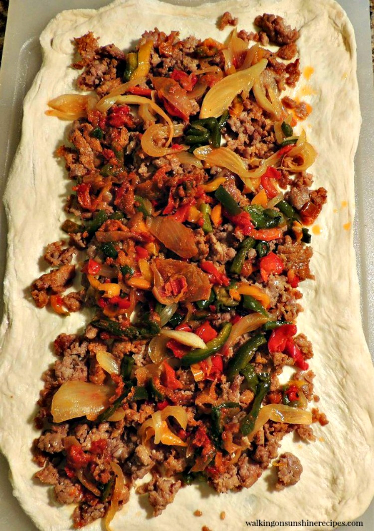 Sausage and peppers on top of rolled out pizza dough 