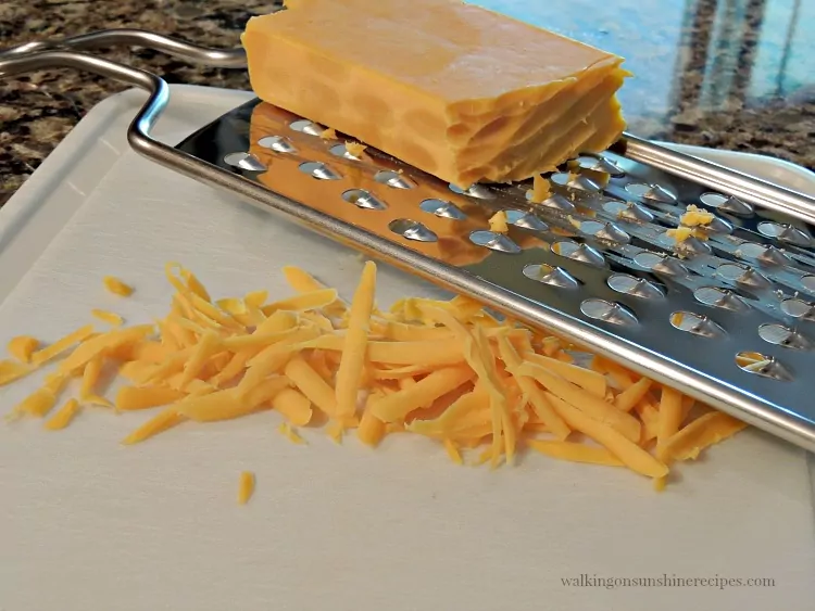 cheddar cheese grated on cutting board.