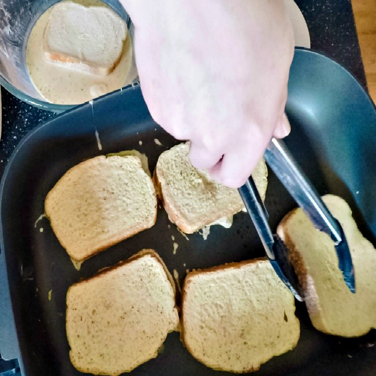 French toast cooking in frying pan with egg mixture