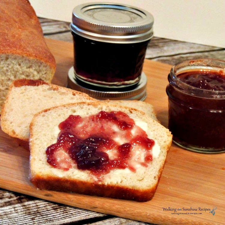 Homemade bread sliced on cutting board with butter and homemade jam. 