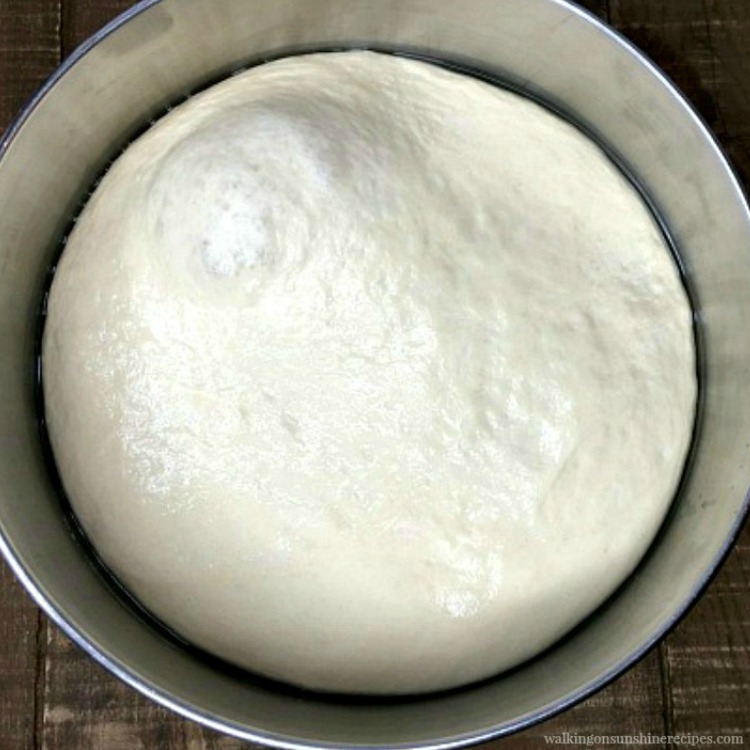 Raw bread dough risen in metal bowl