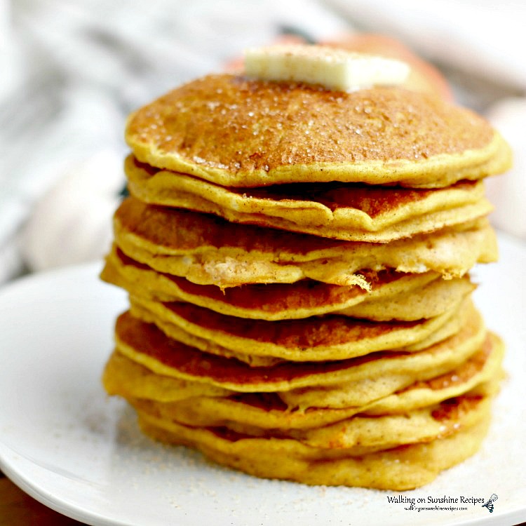 Pancake Mix Pumpkin Pancakes stacked on a white plate with butter and cinnamon sugar sprinkled on top.