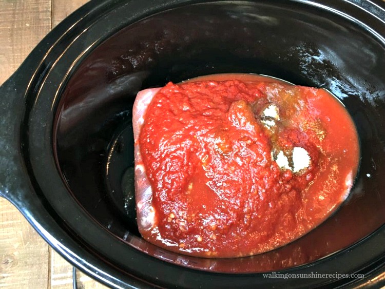 Brisket in crock pot with sauce on top before cooking. 