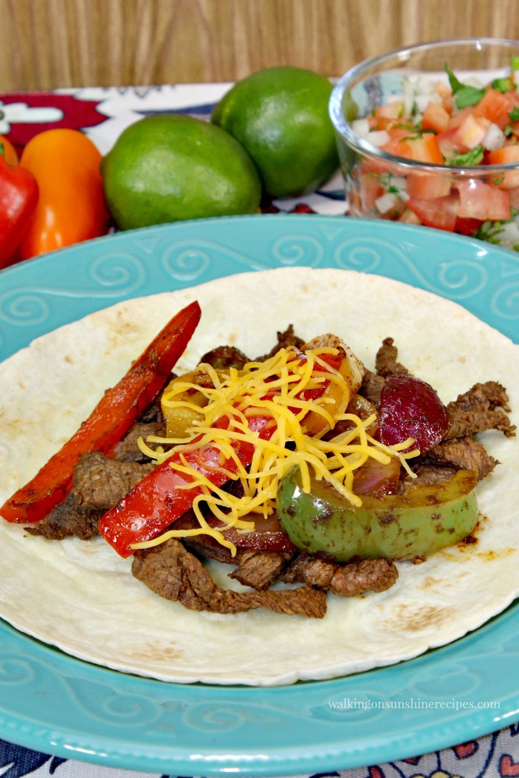 Easy Steak Fajitas on top of Flour Tortillas with Cooked Peppers and Onions and limes. 