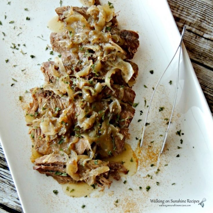 Crock Pot London Broil on white platter with sauteed onions