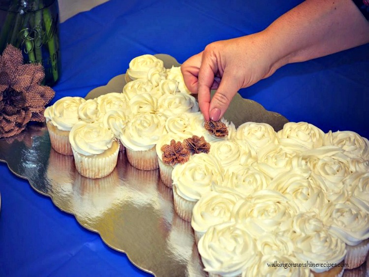 Adding mini burlap flowers to the wedding dress cupcakes. 