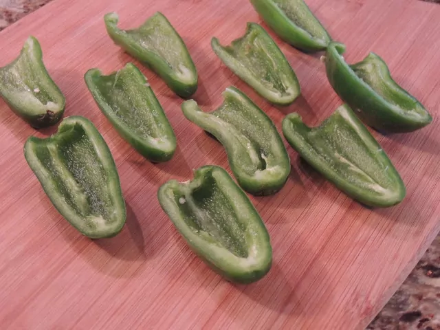 sliced jalapeno peppers in half on cutting board. 