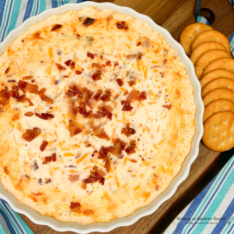 Warm Bacon Cheese Dip on cutting board with buttery crackers. 