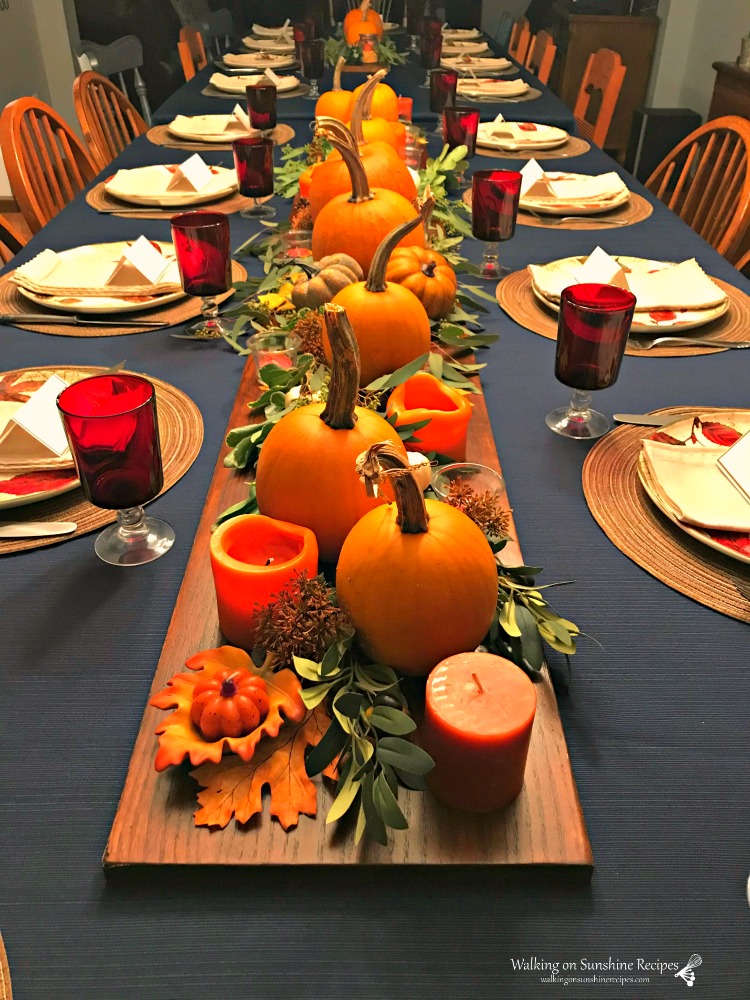 Thanksgiving table set with pumpkins, greenery and candles. 