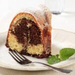 Closeup piece of Marble Bundt Cake on white plate with a sprig of mint from WOS