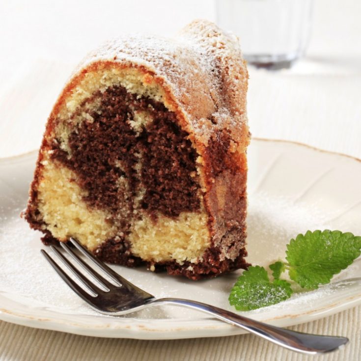 Closeup piece of Marble Bundt Cake on white plate with a sprig of mint from WOS