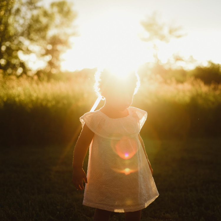 Little Girl in field with sunshine