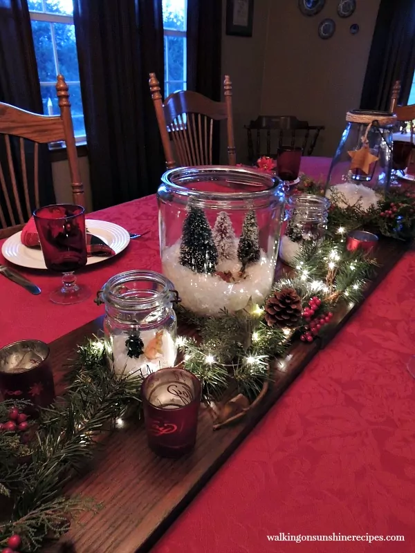 Glass jar terrariums with pine branches make a beautiful centerpiece for Christmas from Walking on Sunshine. 