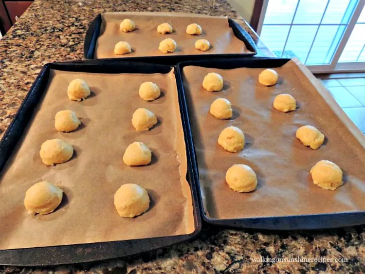 Beautiful mounds of choux pastry ready for the oven on baking trays lined with parchment paper. 