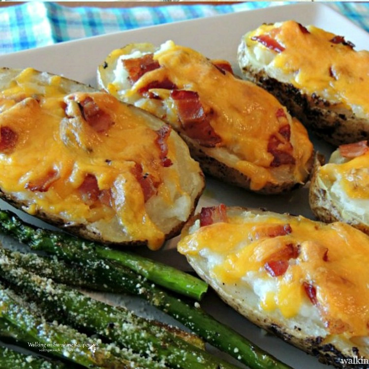 Twice baked stuffed potatoes on white tray with asparagus.