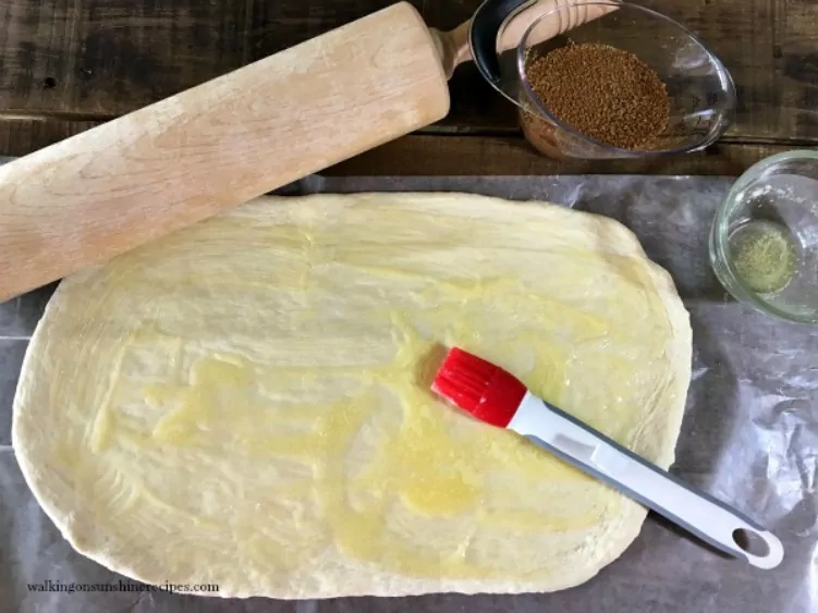Spread melted butter over the thawed frozen bread dough using a pastry brush. 