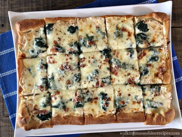 Spinach Alfredo Bacon Pizza on white plate with blue placemat from Walking on Sunshine