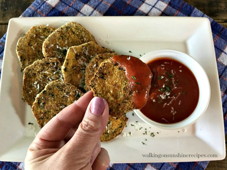 baked crispy eggplant on white platter with tomato sauce in small bowl. 