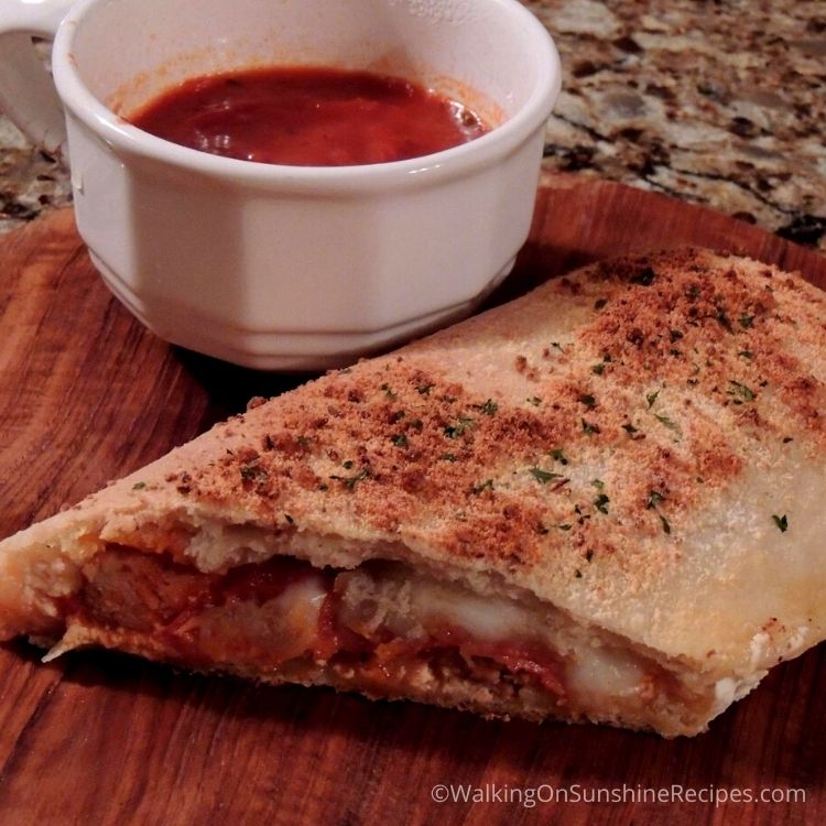 Homemade pizza pocket with marinara sauce in cup. 