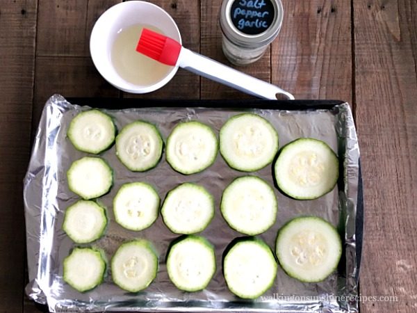 Brush zucchini with oil for Zucchini Pizza Bites from Walking on Sunshine