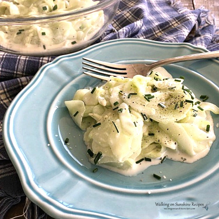 Closeup of German Cucumber Salad made with thinly sliced cucumbers on blue plate