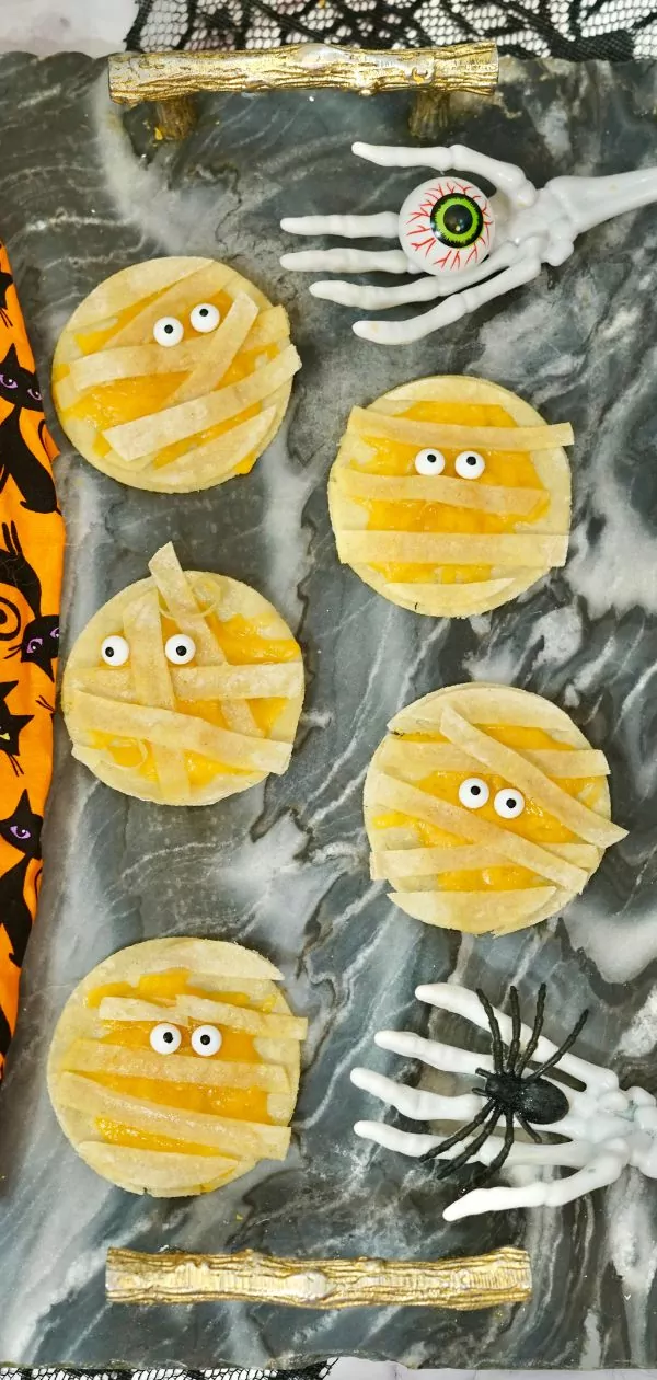 Mummy Quesadillas on a marble serving platter and halloween decor around them.