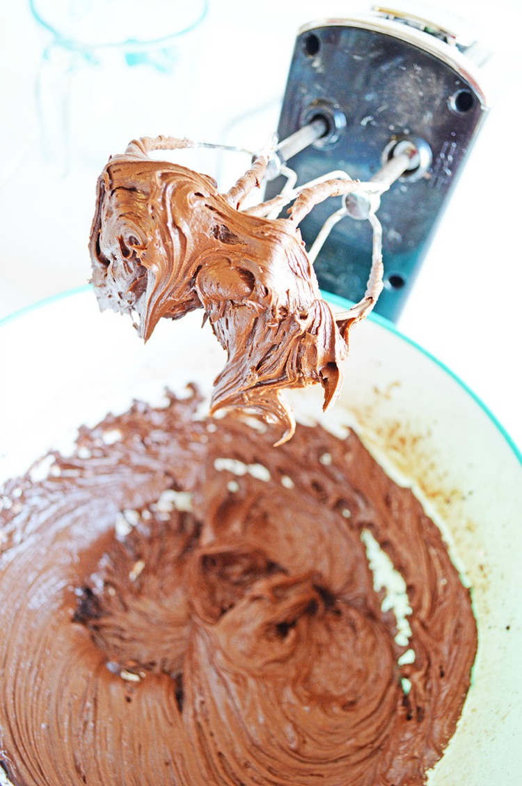 Chocolate frosting in mixing bowl with beaters from mixer