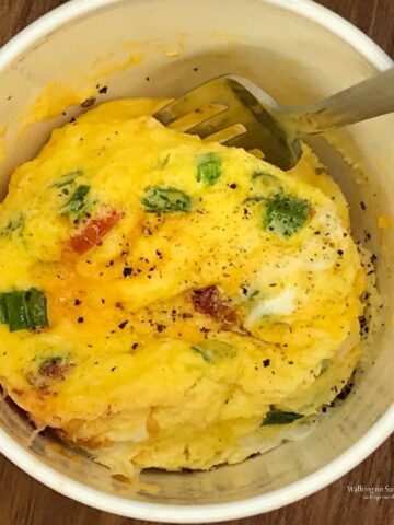 Egg Omelette made with cheese, bacon, green onions in a mug in the microwave