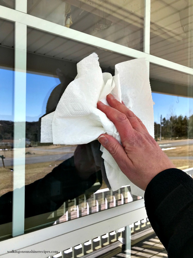 Using a paper towel to clean windows. 