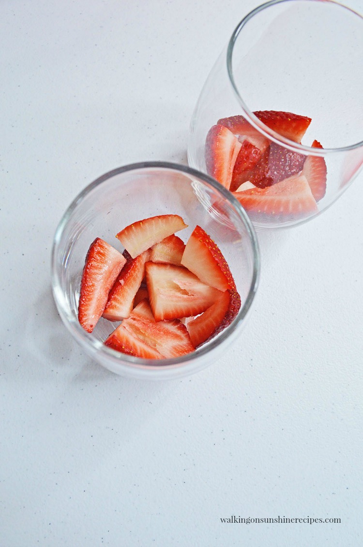 Add strawberries to bottom of glass for No Bake Cheesecake Pudding Parfaits