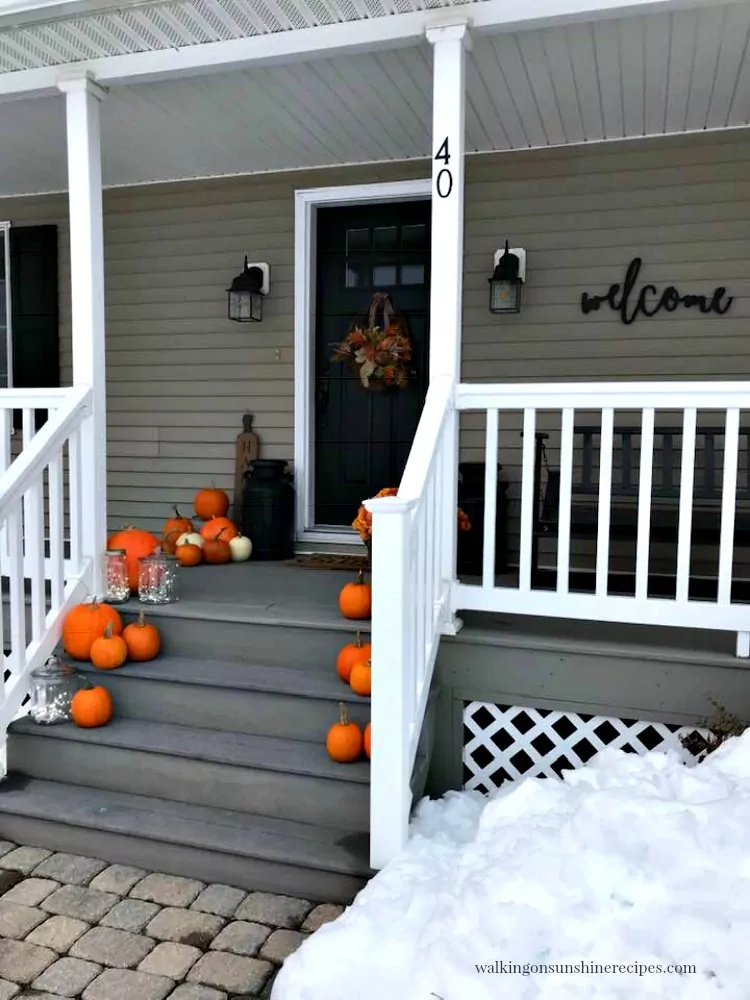 Snow surrounding our front porch with pumpkins and twinkle lights. 