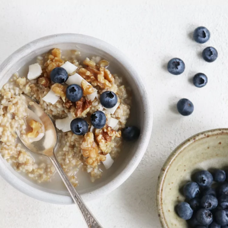 A bowl of oatmeal with blueberries and walnuts. 