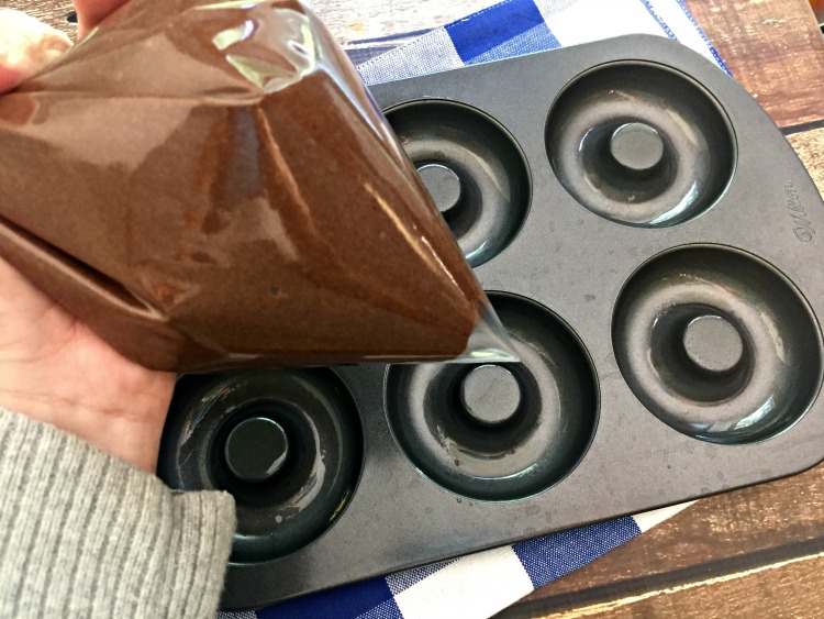 Use a plastic bag to fill the donut pan with chocolate batter. 