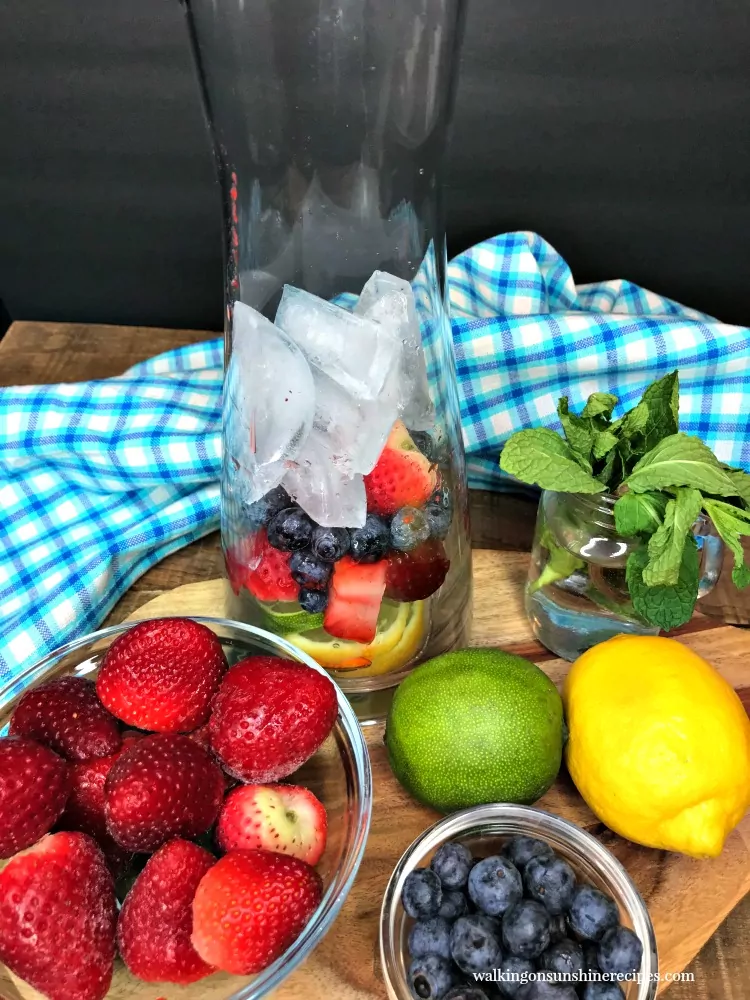 Add ice to infuser bottle with lemons, limes, strawberries and blueberries.