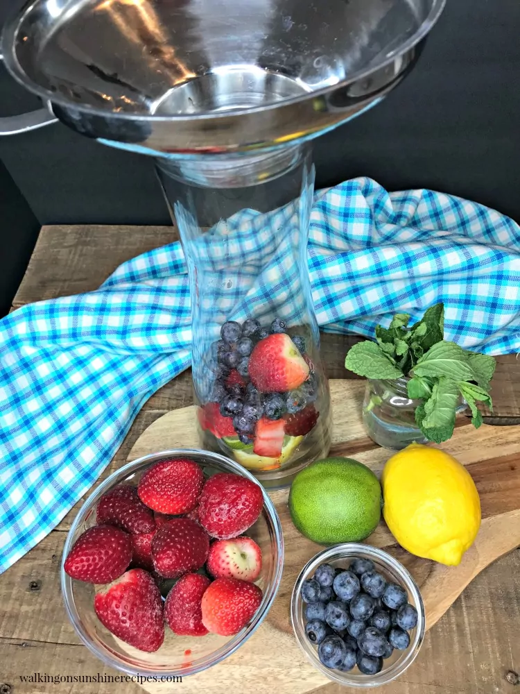 Adding berries and strawberries to glass infuser pitcher.