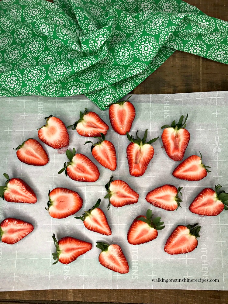 Cheesecake Stuffed Strawberries from Walking on Sunshine Recipes. Halved Strawberries on Parchment Paper