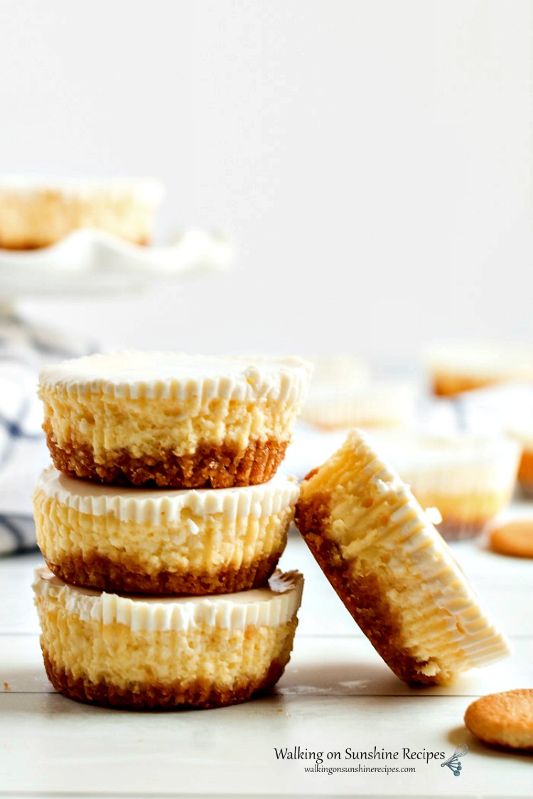 Cheesecake Cupcakes stacked on top of each other on wooden board.
