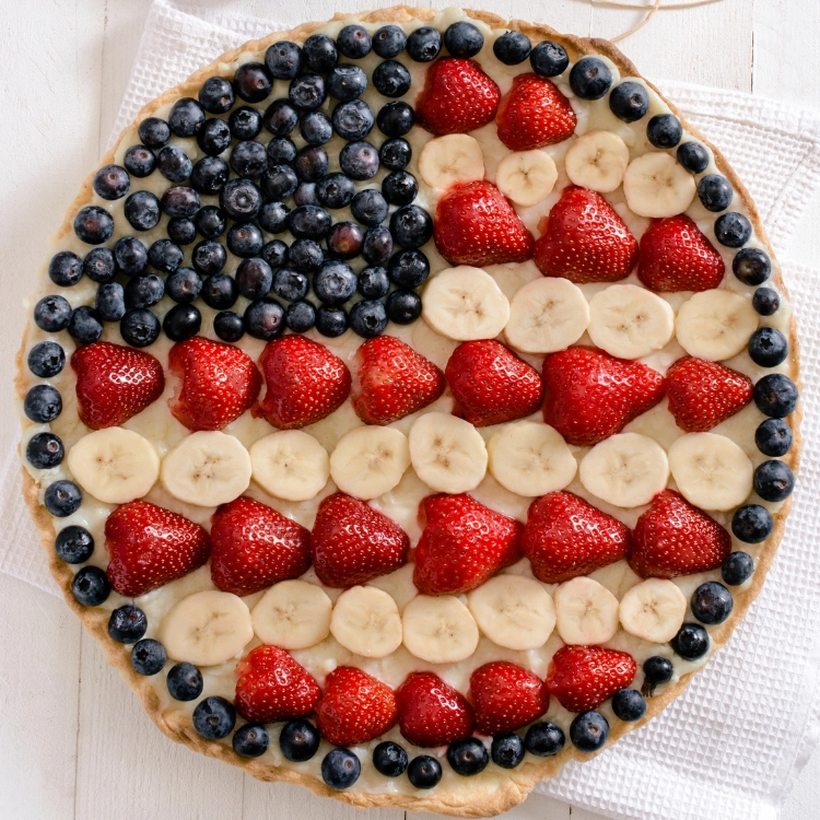 round flag fruit pizza with blueberries, strawberries and bananas. 