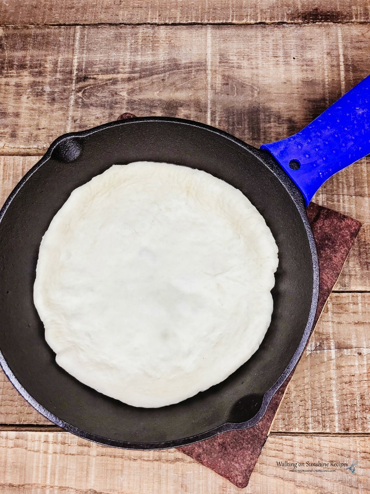 Spread pizza dough in the bottom of the cast iron pan