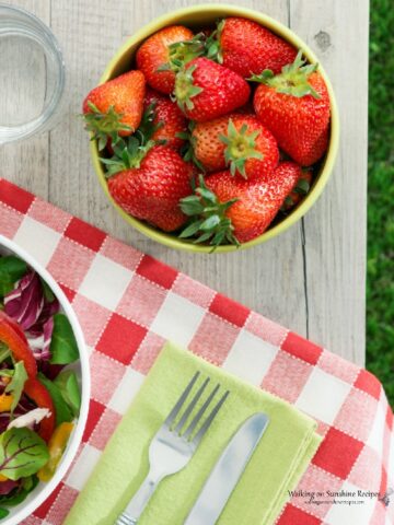 Picnic Table with Red Gingham Tablecloth and Strawberries in Bowl