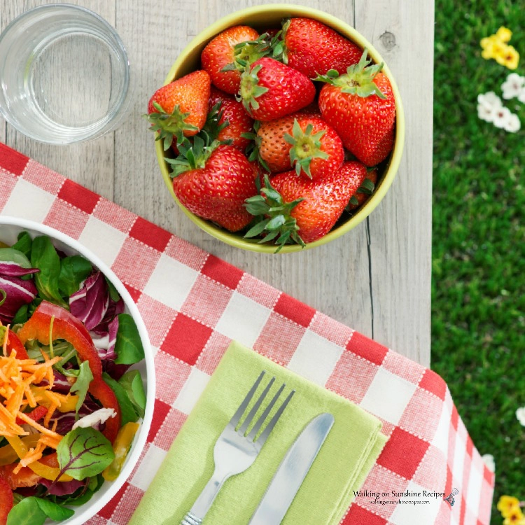 Picnic Table with Red Gingham Tablecloth and Strawberries in Bowl