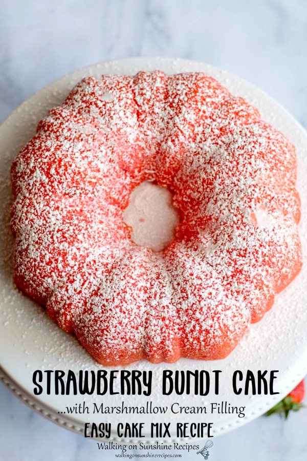 Strawberry bundt cake with powdered sugar on white cake stand. 