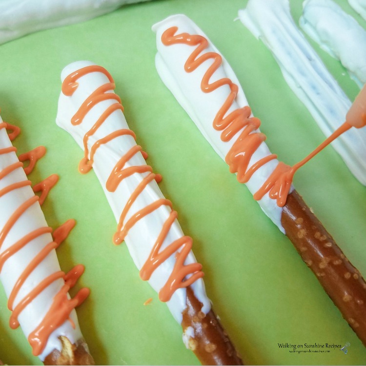 Drizzle melted orange chocolate over pretzels.