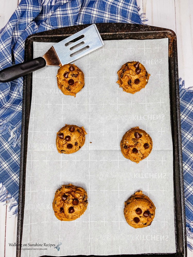 pumpkin cake mix cookies baked on cookie tray with spatula. 
