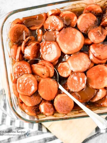 Candied Sweet Potatoes baked in dish with serving spoon from Walking on Sunshine Recipes